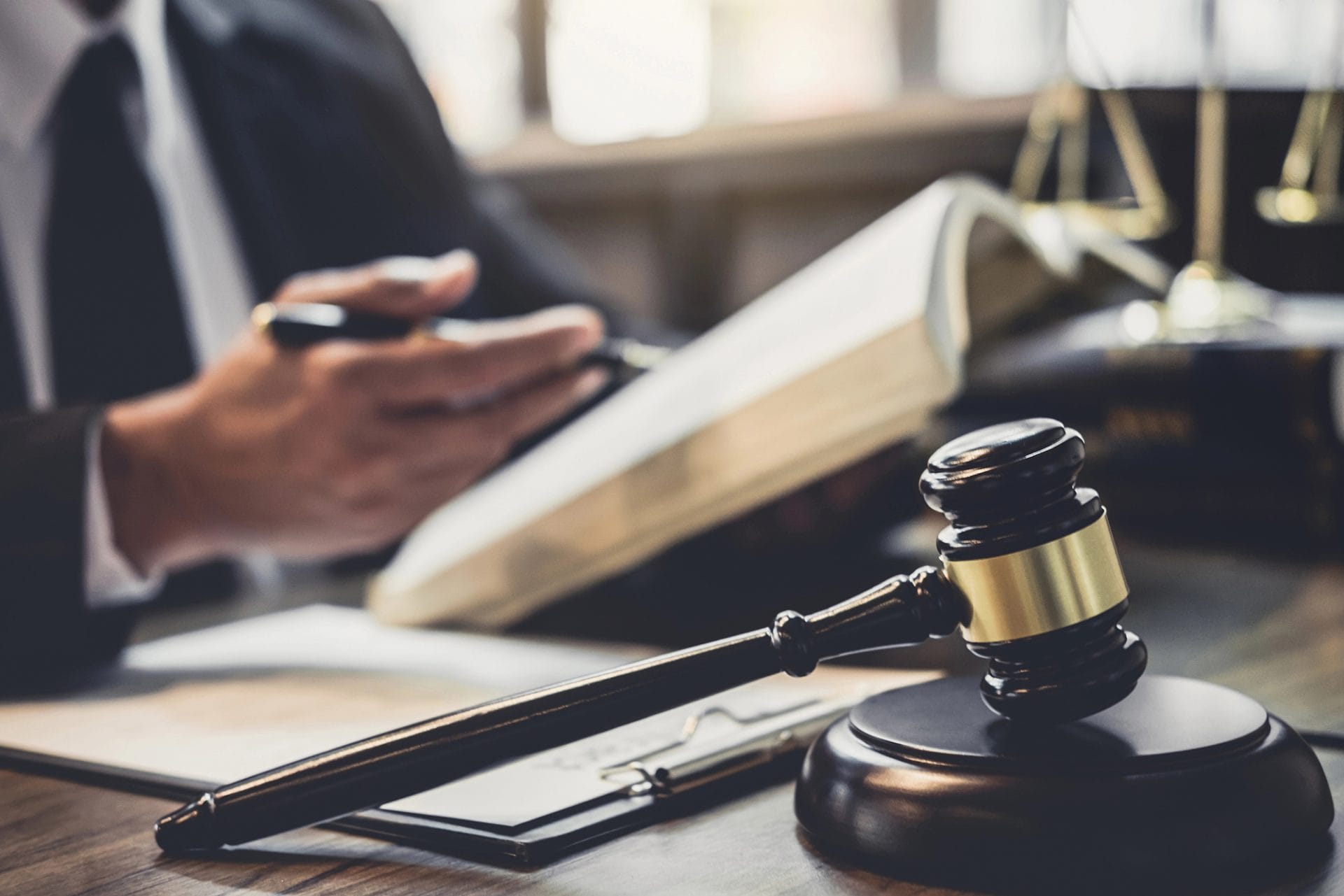 Attorney discussing details about a Trust; sitting at a desk reviewing information in a notebook with a file folder and gavel in the foreground.