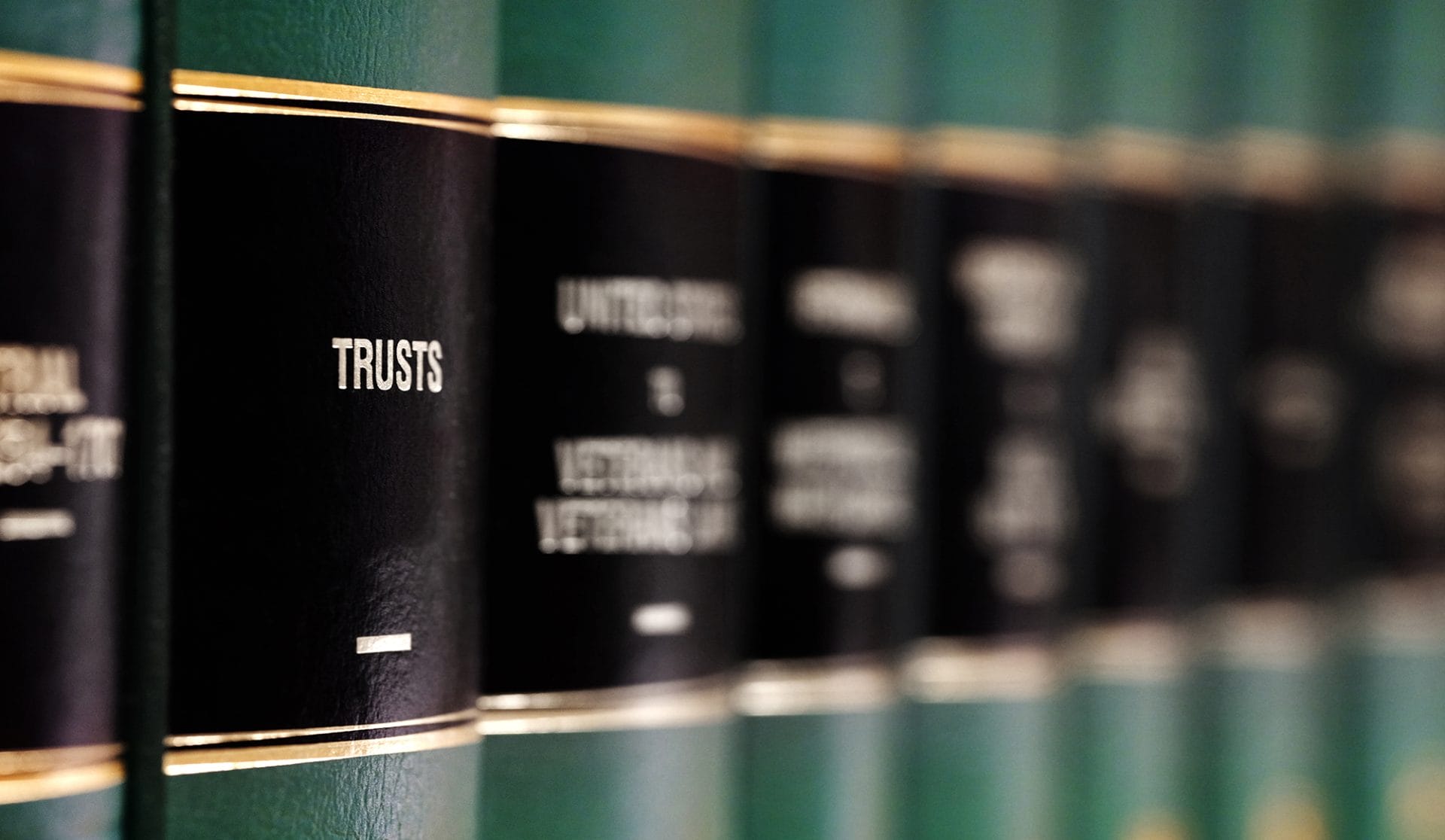 A set of law books in green and black binding with gold lettering; the focus is on the book titled "Trusts."
